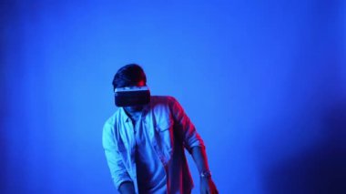 Mutlu dansçı VR gözlüklerini kullanırken enerjik bir hareket yapıyor. Dans ederken ve müzik dinlerken sanal gerçeklik kulaklığı takan sıradan giysili beyaz bir adam. Eğlence konsepti. Aygıt.