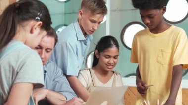 Akıllı robotlar sınıfta dizüstü bilgisayar ekranını işaret ederken, beyaz bir öğretmen yorum yapıyor ya da öğrencilere tavsiye veriyor. Öğretmen bilgisayar kullanırken çeşitli öğrencilerin ders verirken not alması. Öğretim