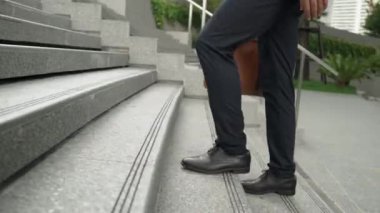 Yakından bakınca iş için çanta tutarken yürüyen zeki bir iş adamının görüntüsü var. Proje yöneticisi çalışmak için merdivenlerden iniyor. Ulaşımı temsil eden, seyahat eden. Bacağa odaklan. Sevinçli..