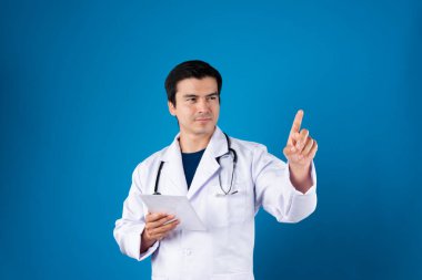 Akıllı doktor, elinde şeffaf tablet, hastalık araştırması verileri tutarak fütüristik teknolojiyle sağlık hizmetleri yenilik arayüzü hologram monitörü ekranını işaret ediyor. Entrika.