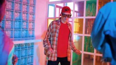 Kafkas dansçısı dans ederken çeşitli arkadaşları gece kulübünde neon ışıkta ayak seslerine bakıyor. Çoklu etnik kökenli hipsterin serbest stil müziğe geçişi ve mutlu bir adamın kameraya bakışıyla. Mutluluk.