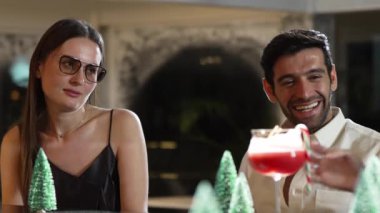 Grup arkadaşı ya da çift, gece kulübündeki neon karlı çam ağacında şenlik için özel bir menü içeceği tatmak için tezgahta punç kokteyli içmeyi tartışıyor. Vinosity.