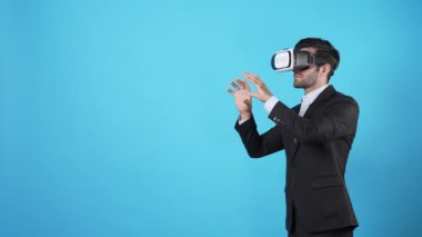 İş adamı artırılmış gerçeklik teknolojisi kullanarak veri yönetiyor. Yatırımcıların VR gözlük takması ve pazarlama stratejisini planlarken mavi arka planda durması. Aygıt.