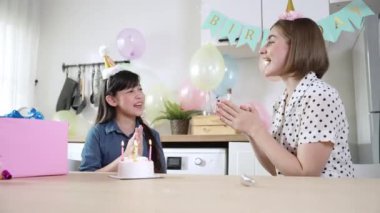 Enerjik kız ve anne birlikte müzik eşliğinde doğum günü şarkısı söylüyorlar. Kafkasyalı anne doğum gününü yemek odasında renkli balonla süslenmiş pastayla kutladı. Pedagoji.