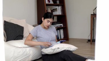 Kanepede oturan bir kadın ders kitabı okuyarak sosyal ve mesleki teknoloji bilgisini artırır ya da akıllı bir anne olmak için çocuk yetiştirir. Hayat boyu öğrenme konsepti. Uyumsuzluk.
