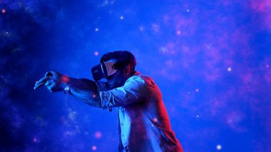 Yetenekli oyuncular silah olarak el ele tutuşup VR gözlük takıp atış oyunu oynayarak metaevrene girebiliyor. Çekici erkek model mavi arka planda dururken hareket ediyor ve oyuncuyu hedef alıyor. Aygıt.