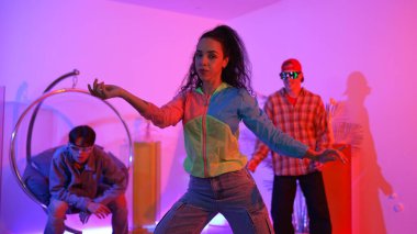 Çekici mutlu dansçı kameraya bakarken zeki kadın neon ışıkla kafiyeli hareket ediyor. Profesyonel İspanyol şarkıcı çeşitli arkadaşlarıyla renkli kıyafetler giyerken break dans yapıyor. Mutluluk.