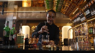 Zeki Asyalı barmen bardakta karıştırılmış alkol şurubunu buzla karıştırıyor. Çünkü kayanın üzerinde kamera var. Gece kulübünde taze kokteyl kokteylleri karıştırıyor. Vinosity.
