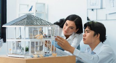 Kooperatif mühendis ekibinin portresi ev modelini ölçmek için cetvel ve mimari ekipmanlar kullanarak birlikte çalışıyor. Yaratıcı iş tasarımı ve takım çalışması konsepti. Tertemiz...