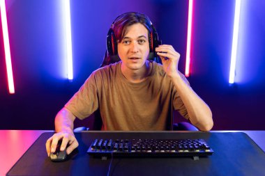 Kazanmak için çevrimiçi oyun oynayan akıllı flama makinesinin sunucu kanalı, neon ışıklı odada seçilen takım yarışması için izleyicilerle birlikte canlı yayında canlı yayında kulaklık takıyor. Bireysel.