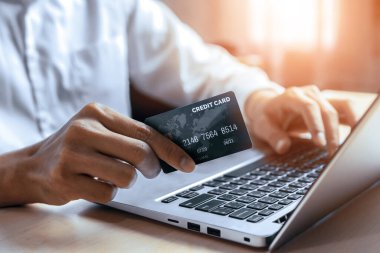 Genç adam, laptop bilgisayar başvurusu ya da web sitesinde online alışveriş yapmak için kredi kartı kullanıyor. E-ticaret ve online alışveriş konsepti. uds