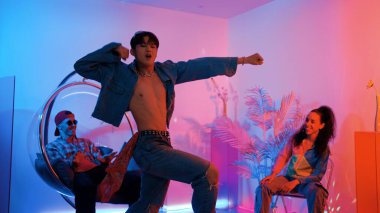 Çok kültürlü bir arkadaş kürsüde otururken Asyalı yetenekli bir dansçı modern müziğe geçiyor. Profesyonel dansçı, hipster takımı tezahürat yaparken ve desteklerken enerjik adımlar atıyor. Mutluluk.