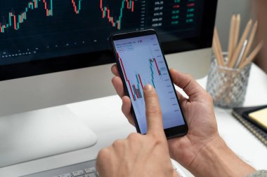 Akıllı borsa yatırımcıları ekranda akıllı telefon ile piyasa borsasını işaret ederek dizüstü bilgisayarın yanı sıra en yüksek dinamik yatırım oranını göstererek, modern işyerindeki veri planlamasına odaklanıyorlar. Bireysel.