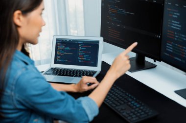 İnternet sitesinde kodlama programı uygulaması olan ve kot gömlek giyen bilgisayar hakkında bilgi veren IT geliştiricisi genç bir Asyalı kız. Güvenlik programlarıyla çevrili iki ekran. Taktik.
