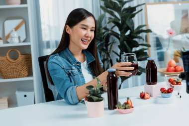 Gülümseyen, güzel Asyalı genç, lezzetli karışık çilek ve kiraz suyu detoksu içeceklerini inceleyen, sosyal medyada özel promosyon satışı için sağlıklı ürünler sergileyen. Taktik.