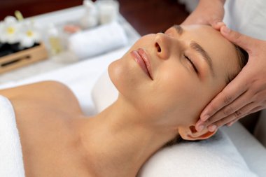Kafkasyalı kadın stres önleyici kafa masajından ve lüks tatil beldesi ya da otel spa salonundaki modern ışık ortamında yüz güzelliği eğlencelerini şımartmaktan hoşlanıyor. Sessiz.