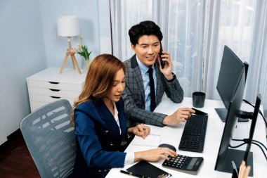 Gülümseyen Asyalı işadamı komisyoncu dinamik borsa veritabanını arıyor. Kadın iş ortağı, iç işyerindeki kar eden uygulama programını karşılaştıran ekranlara işaret ediyor. İnfobahn.