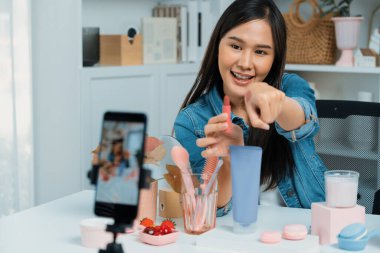 Genç, güzel Asyalı kozmetik makyaj ruju matte pastel rengini modern odadaki sosyal medyada kol testi tanıtımında en çok satanlar listesinde gösteriyor. Taktik.