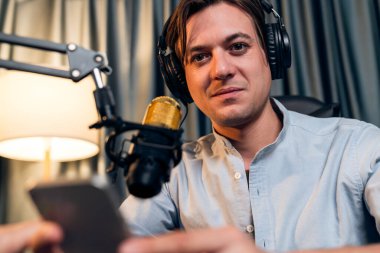 Sunucu kanalı akıllı yayıncı canlı sosyal medyada kamera önünde yüz portresi yapıyor. Etkilenen yayıncı, modern ofis stüdyosunda kulaklık takıyor. Bireysel.