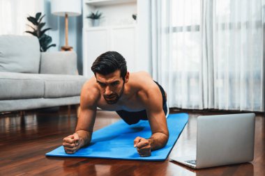 Atletik ve sporcu adam, evdeki formda fiziğe ve sağlıklı spor yaşam tarzına uygun vücut egzersizi sırasında spor minderinde kalas yapıyor. Gaiety evde egzersiz eğitimi.