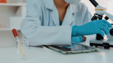 Laboratuvar kimya araştırmacısı mikroskop kullanarak yeni ilaç ya da tedavi geliştirir. Laboratuvar mikrobiyoloji ekipmanları ile bilimsel uzmanlık ile sağlık hizmetlerinin teknolojik gelişimi. Ağır çekim. Katı.