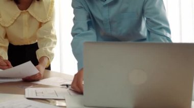 Mimarlık ve güvenlik mühendisi, modern ofiste dizüstü bilgisayarda mimari belge ve ahşap blokla sergilenen planlar hakkında tartıştı. - Yakın çekim. Tanımlama.