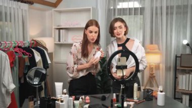 İki kadın nüfuzlu partner sosyal medya veya blog için canlı yayın yapan video klip inceleme derisi çekiyorlar. Kozmetik stüdyosu ışıklandırması olan genç bir kız pazarlama oturumu çevrimiçi yayın yapıyor.
