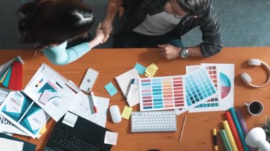 Akıllı tasarımcının renkli paletlerden renk seçmesine yardım ederken yukarıdan aşağı görünümü. Dizüstü bilgisayardan logoya bakarken birlikte çalışan ve planlayan iş adamlarının hava görüntüsü. Sempozyum.