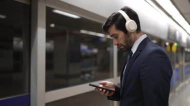 Proje yöneticisi tren istasyonunda şarkı seçmek için cep telefonu tutarken kulaklık takıyor. Zeki iş adamı bulanık geçmişi olan treni beklerken saati kontrol ediyor. Sevinçli..