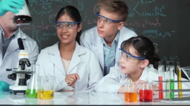 BTMM sınıfında kimya teorisi üzerine karatahta deney yaparken deney yapan bir kız. Karışık ırkları olan bir grup lise öğrencisi ve öğretmen birlikte bilimsel aktivite yapıyorlar. Öğretim