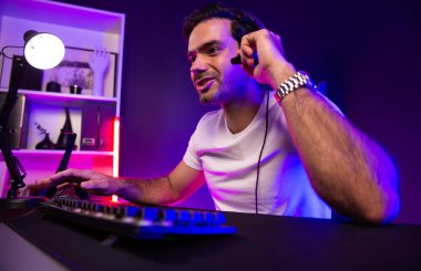 Akıllı oyun kurucusu, dijital neon ışıklandırma stüdyosundaki sosyal medya uygulamasında başkalarıyla iletişim kurmak için kulaklık ve mikrofon kullanan takım üyeleriyle konuşuyor. Tahmin et..