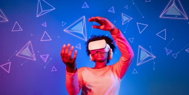 VR gözlüklü Afrikalı kız mavi ve pembe arka planda duruyor ve yüzen geometrik şekle bakıyor. Heyecanlı insan görsel gerçeklik dünyasına giriyor. Teknoloji yeniliği. Yaratıcılık.