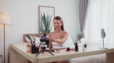 Genç kadın canlı yayına başlıyor. Sosyal medya için güzellik ve kozmetik video içeriği. Güzellik blogcusu kameraya gülümserken seyircilere ve takipçilere güzellik bakımını gösteriyor. Düzenle