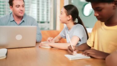 Zeki öğretmen çeşitli öğrenciler otururken ve test yaparken soruyu cevaplıyor. Çok kültürlü çocuklar yazarken ya da not alırken öğretmenler dizüstü bilgisayarlarını kullanarak verileri analiz ediyor ve kağıda bakıyor. Öğretim