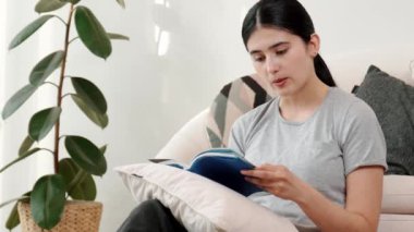 Kanepede oturan bir kadın ders kitabı okuyarak sosyal ve mesleki teknoloji bilgisini artırır ya da akıllı bir anne olmak için çocuk yetiştirir. Hayat boyu öğrenme konsepti. Uyumsuzluk.