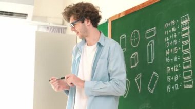 Kafkas öğretmeni tahtada dururken öğrenciye bakıyor. Profesyonel eğitmenin öğrettiği düşük açılı kamera ve çeşitli öğrencilerin sorularına cevap verirken matematik teorisini açıkla. Pedagoji.