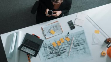 Üst düzey inşaat mühendisi yapışkan notlar yazıyor ve dizüstü bilgisayara bakıyor. Hava görüntüleme mimarı bilgisayar analizi yaparken toplantı masasında oturuyor ve bina yapısını hesaplıyor. Hizalama.