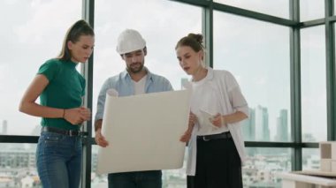 Proje planına bakarken tasarımla ilgili düşünen, paylaşan, beyin fırtınası yapan profesyonel mimar mühendis takımı. Yönetici planı dinlerken genç mimar plan yapıyor. İzleme