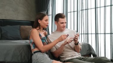 Genç çift, kredi kartıyla ödemek için internet üzerinden ödeme uygulaması ve dijital cüzdan kullanarak yatak odasında oturuyor. Mobil internet üzerinden alışveriş ve modern alımlar. Düzenle