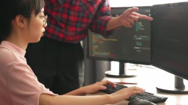 Yavaş çekimde geri uç veya yazılım geliştirici yöneticisi ekibini monitörde hata ayıklama ve karmaşık kod algoritmalarını çözmede yeni uygulama programı geliştirmede denetliyor. Filizlenen