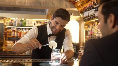 Akıllı barmen, lüks bir tezgahta arkadaşını beklerken limonlu cin kokteyli ikram ediyor. Barmen, canlı gece hayatı parti atmosferinde mükemmel hizmet veriyor. Vinosity.