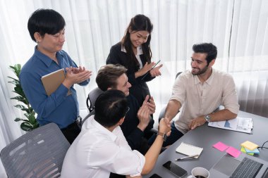 Çeşitli ofis çalışanları stratejik iş pazarlama toplantısı üzerine anlaşma yaptıktan sonra el sıkışıyor. Takım çalışması ve olumlu tutum verimli ve destekleyici bir iş yeri yaratır. Tedbirli