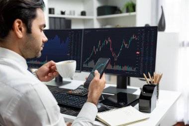 Elinde telefon dinamiğine odaklanan kahve fincanı tutan borsa yatırım ekranı veri analizini karşılaştırarak iç işlerinde yüksek kârlı finans teknolojisi pazarına yatırım yapıyor. Tahmin et..