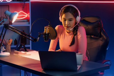 Geceleri podcast 'te olumlu konuşmalar yapan, pembe neon ışıklı modern stüdyoda sunum için dizüstü bilgisayar kullanan, gülümseyen, genç, güzel Asyalı bir etkileyiciydi. Taktik.