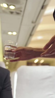 Kabin ekibi uçaktaki yolculara su servis ediyor. Havayolu taşımacılığı ve turizm kavramı.