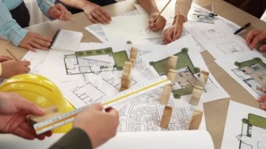 Mimari belge, ölçüm aracı ve ahşap blokların modern ofiste etrafa saçıldığı bir masa üzerinde yapı inşaatı ile ilgili mimar ve güvenlik mühendisi tartışması. Tanımlama.