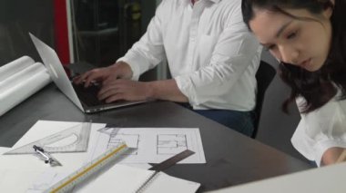 Bir grup mimar mühendis birlikte çalışıyor ve ofis tasarımı hakkında tartışıyorlar. Genç mühendis ev modelini ölçerken yönetici dizüstü bilgisayar kullanıyor. İş tasarımı konsepti. Yönlendirici.