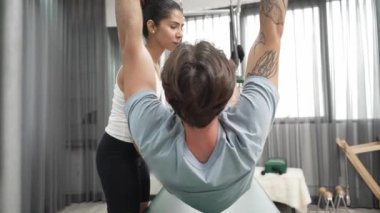 Eğitmen rehberliğinde Pilates Cadillac 'ta ters bacak yükseltme pratiği yapan sağlıklı bir müşteri. Çekirdek dayanıklılığını ve üst vücut dengesini arttırmak için Cadillac 'ı geren adam. Alışkanlık.