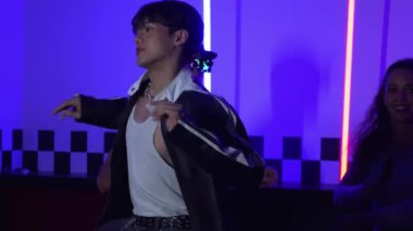 Gündelik gömlekli, gözlüklü, neon ışıkla dans eden farklı insanlar. Gece kulübünde dans ederken kameraya bakıp sokak dansı yapan çok kültürlü break dansçı. Mutluluk.
