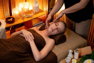 Beyaz kadın stres önleyici kafa masajı yapmaktan ve lüks otel veya otelde sıcak mum ışığında yüz güzelliği eğlencesi yapmaktan zevk alıyor. Sessiz.